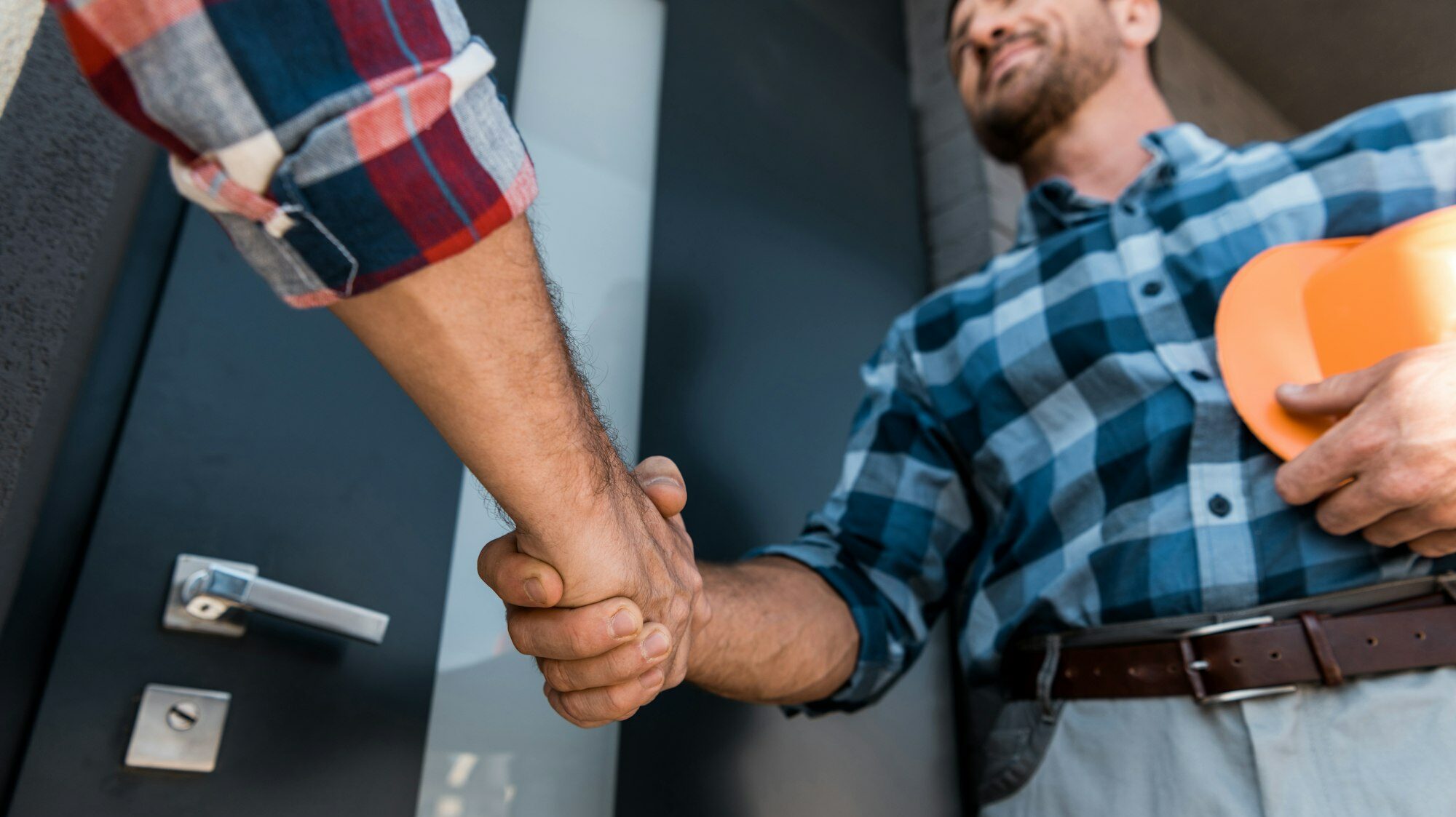 cropped view of men shaking hands while standing near door cropped view of men shaking hands while standing near door